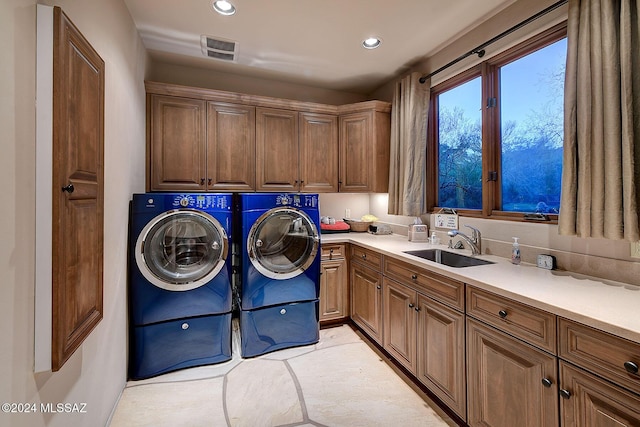 clothes washing area with cabinets, separate washer and dryer, and sink