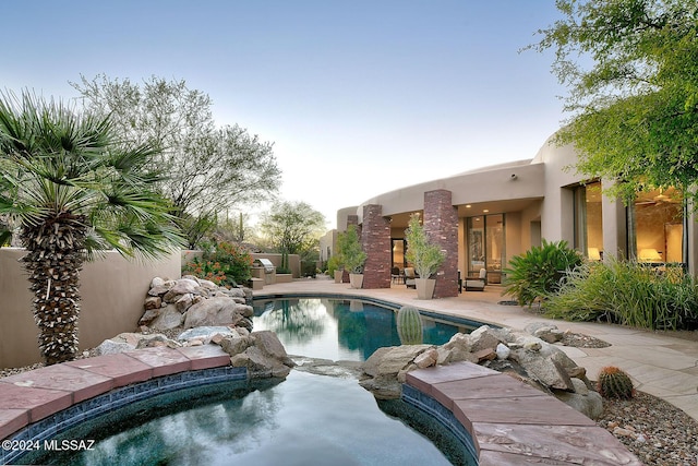 pool at dusk featuring a patio area