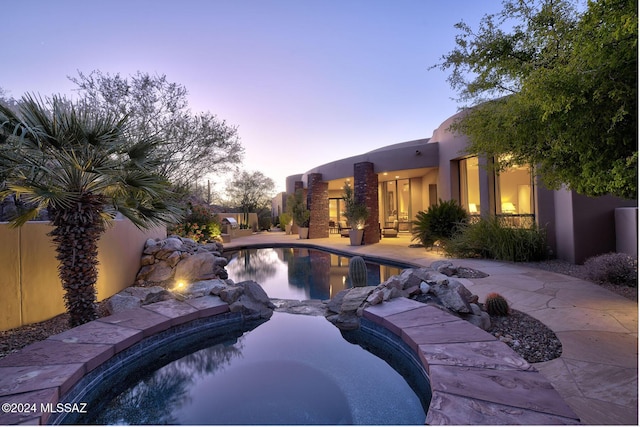 pool at dusk with a patio area