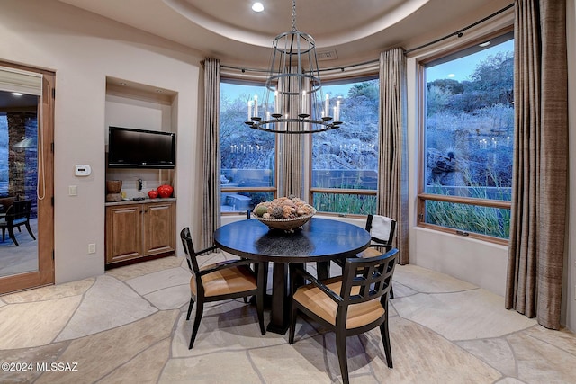 dining area featuring a raised ceiling and a chandelier