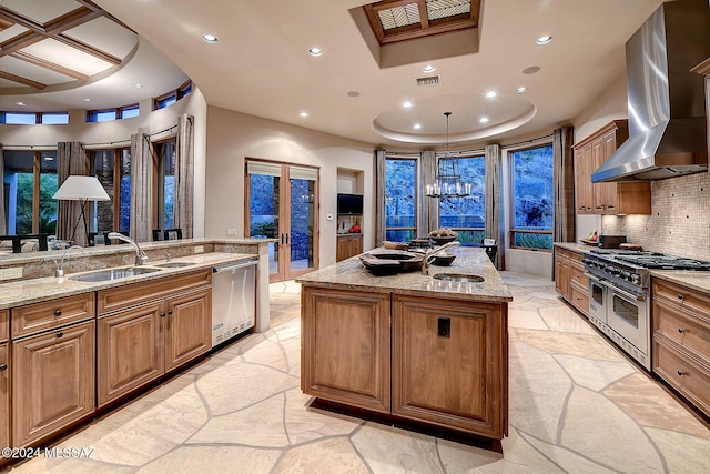 kitchen featuring exhaust hood, a spacious island, sink, light stone counters, and stainless steel appliances