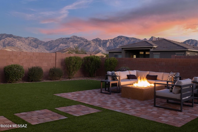 patio terrace at dusk with outdoor lounge area, a mountain view, and a yard