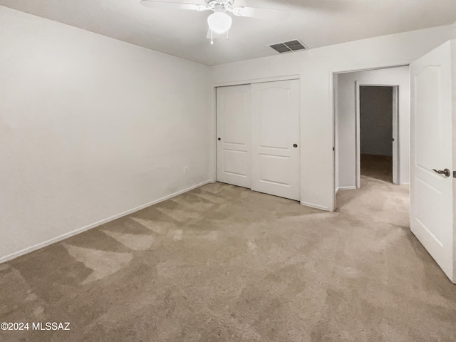 unfurnished bedroom with ceiling fan, a closet, and light colored carpet