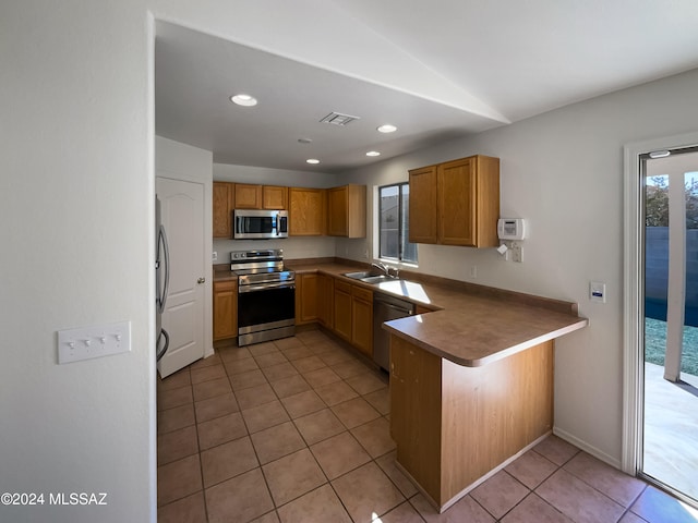 kitchen featuring kitchen peninsula, sink, light tile patterned floors, and stainless steel appliances