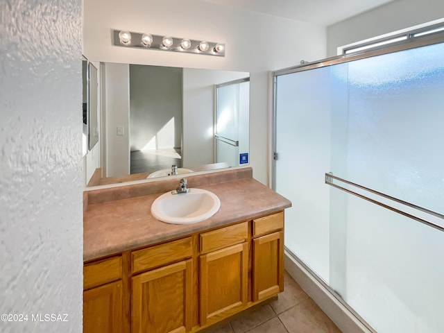 bathroom featuring vanity, walk in shower, and tile patterned flooring