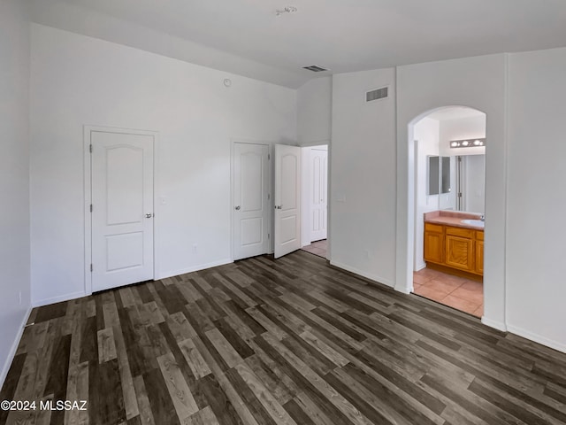 unfurnished bedroom featuring ensuite bathroom, sink, a closet, and dark hardwood / wood-style flooring