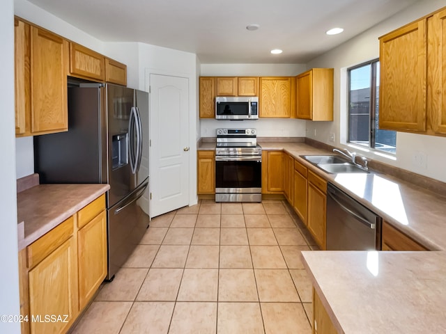 kitchen with appliances with stainless steel finishes, sink, and light tile patterned floors