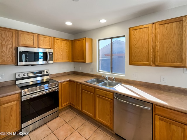 kitchen with stainless steel appliances, light tile patterned floors, and sink