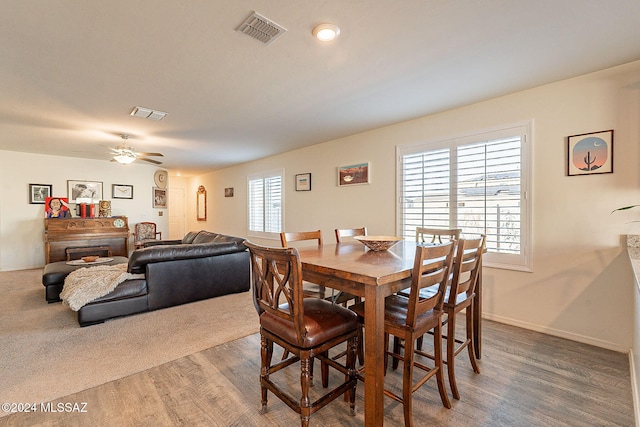 dining space with hardwood / wood-style flooring, plenty of natural light, ceiling fan, and a fireplace