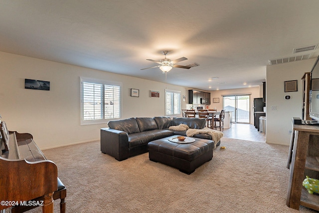 carpeted living room with ceiling fan and plenty of natural light