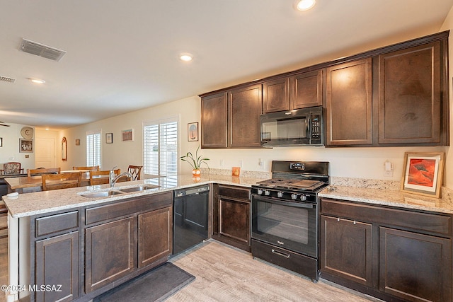 kitchen featuring black appliances, light wood-type flooring, kitchen peninsula, and sink