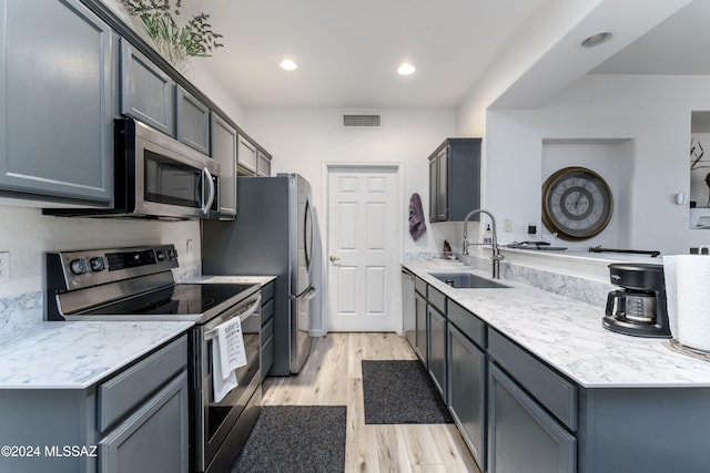 kitchen featuring gray cabinetry, sink, light hardwood / wood-style flooring, and appliances with stainless steel finishes