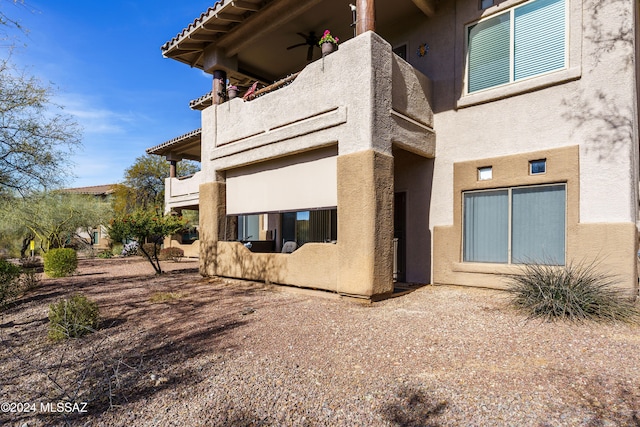 back of house with ceiling fan and a balcony