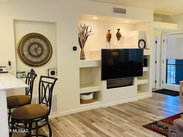 living room featuring built in features and light hardwood / wood-style flooring