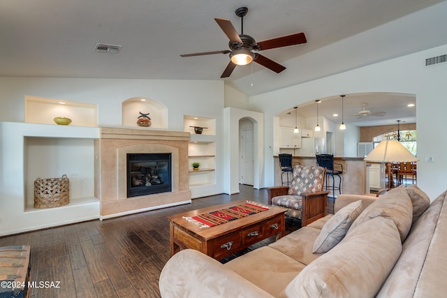 living room with lofted ceiling, dark wood-type flooring, ceiling fan, and built in shelves