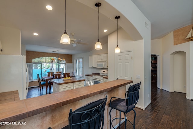 kitchen with white appliances, butcher block counters, white cabinetry, a kitchen breakfast bar, and decorative light fixtures