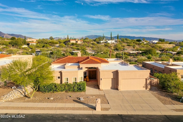 view of front of home featuring stucco siding, concrete driveway, a mountain view, a garage, and a tiled roof