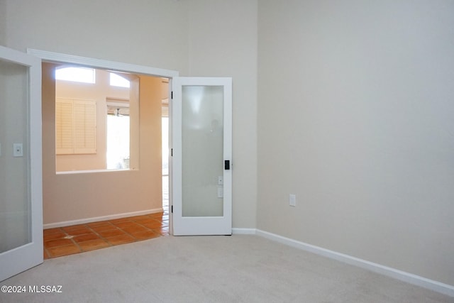 spare room featuring light carpet and french doors