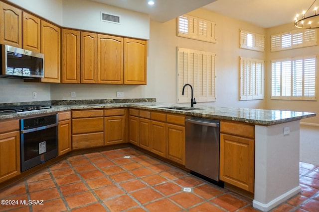 kitchen featuring tile patterned floors, sink, kitchen peninsula, stainless steel appliances, and a chandelier