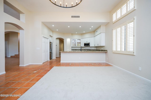 kitchen with arched walkways, stainless steel microwave, a sink, and baseboards