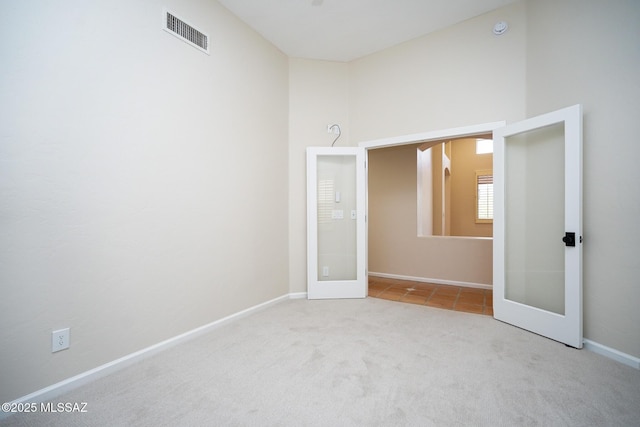 carpeted empty room featuring baseboards, visible vents, and french doors