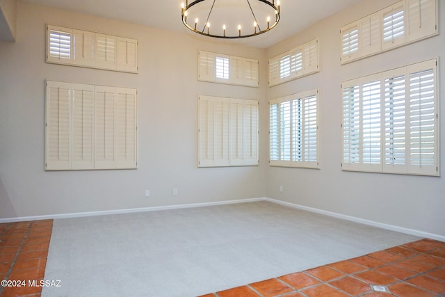 unfurnished room featuring carpet and a notable chandelier