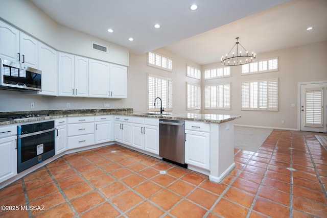 kitchen featuring a peninsula, a sink, visible vents, white cabinetry, and appliances with stainless steel finishes