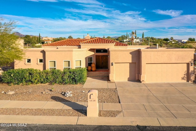 view of front of house with a garage, driveway, a tile roof, a chimney, and stucco siding