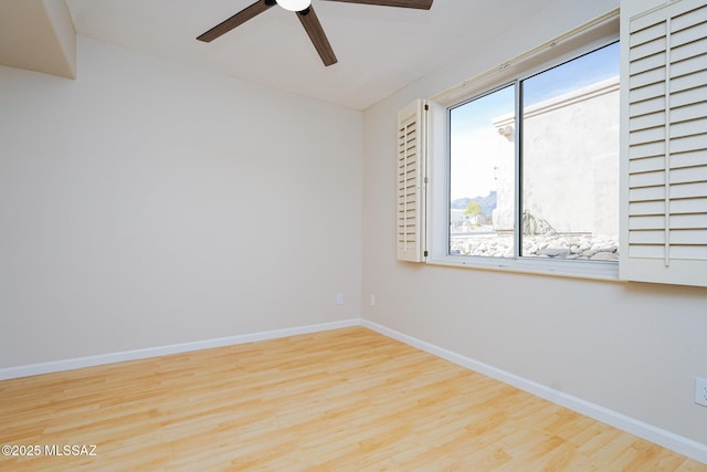 empty room with ceiling fan, wood finished floors, and baseboards