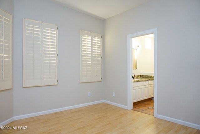 unfurnished bedroom featuring connected bathroom and light hardwood / wood-style floors