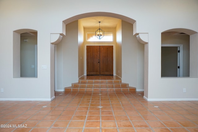 tiled entryway with a notable chandelier