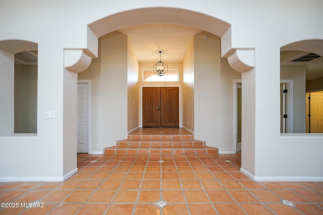 corridor with baseboards, visible vents, a chandelier, and light tile patterned flooring