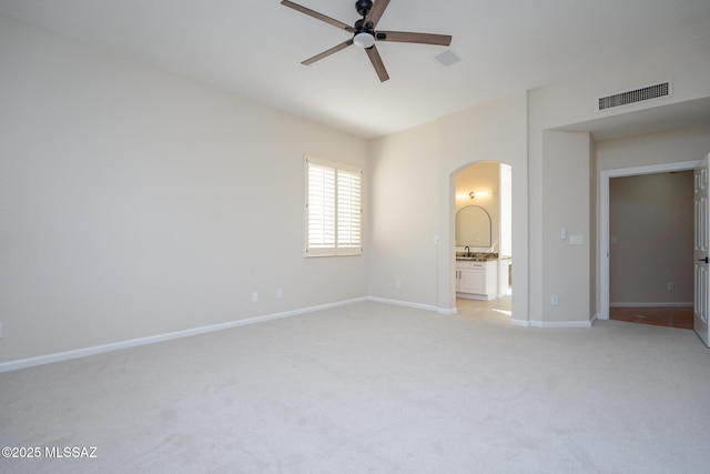 unfurnished bedroom with light carpet, visible vents, arched walkways, and baseboards