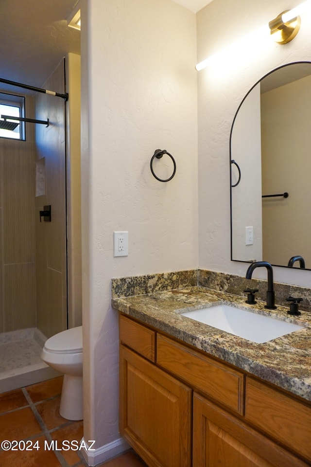 bathroom with tile patterned floors, vanity, toilet, and a tile shower