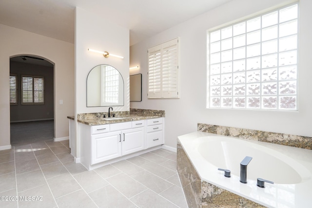 full bathroom featuring tile patterned flooring, baseboards, a bath, and vanity