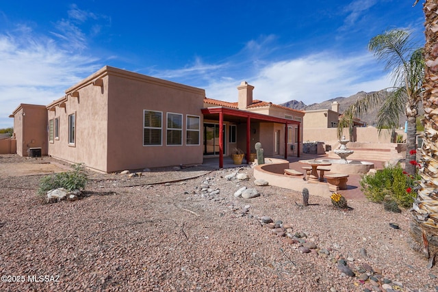 back of property featuring central AC unit, fence, stucco siding, a chimney, and a patio area