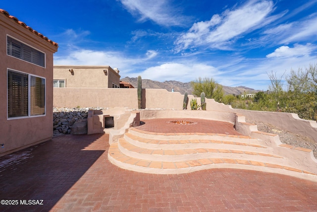 view of patio with a fire pit, fence, and a mountain view