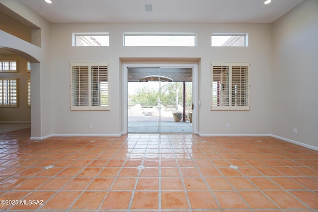 foyer with a wealth of natural light, arched walkways, and light tile patterned floors