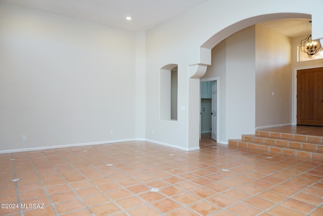 unfurnished room with a notable chandelier, light tile patterned flooring, and a towering ceiling