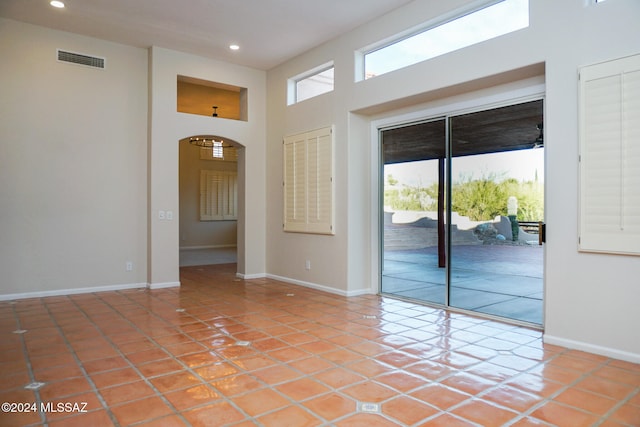 tiled empty room with a high ceiling and a wealth of natural light