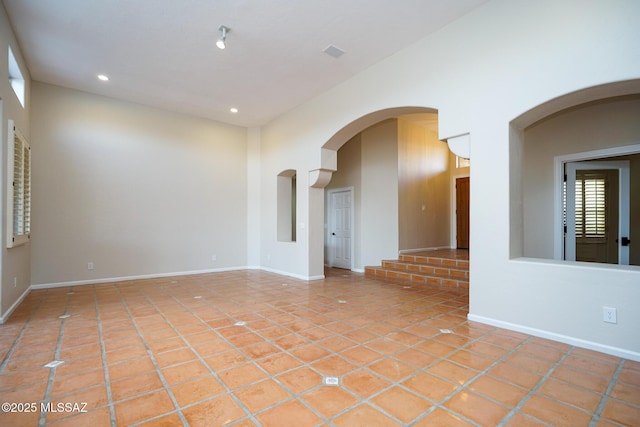 empty room featuring baseboards, recessed lighting, a towering ceiling, and tile patterned floors