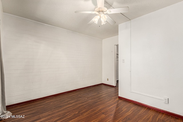 unfurnished room featuring dark hardwood / wood-style flooring, a textured ceiling, ceiling fan, and brick wall