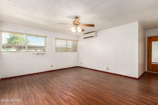 empty room featuring a wall mounted AC, a textured ceiling, and dark hardwood / wood-style floors