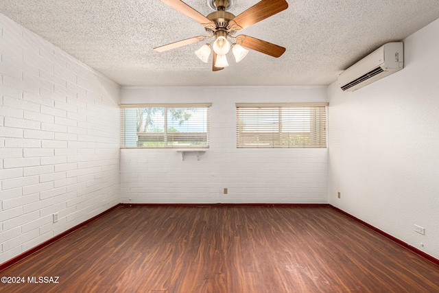 unfurnished room with a wall unit AC, dark wood-type flooring, a textured ceiling, and ceiling fan