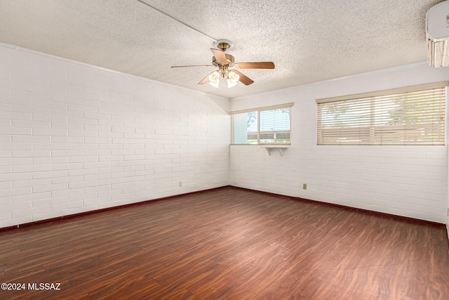 unfurnished room with ceiling fan, a textured ceiling, dark hardwood / wood-style floors, and brick wall