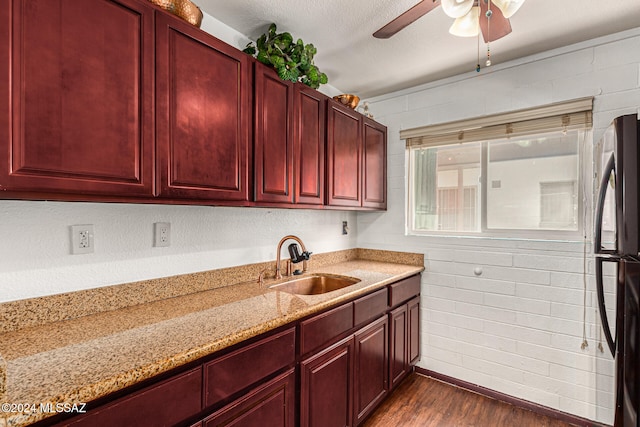 kitchen featuring stainless steel refrigerator, sink, light stone countertops, a textured ceiling, and dark hardwood / wood-style flooring