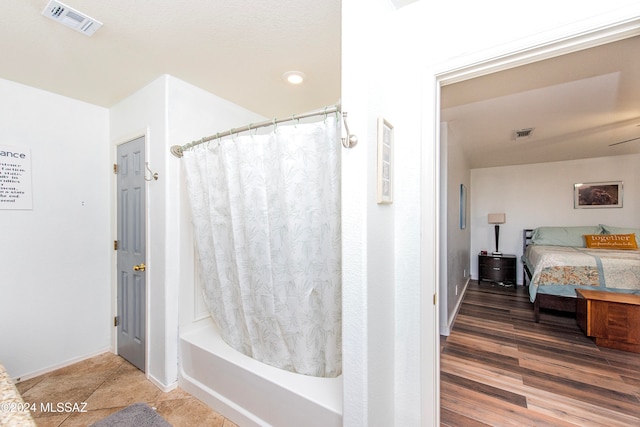 bathroom featuring hardwood / wood-style flooring, ceiling fan, and shower / tub combo