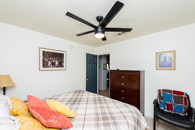 bedroom featuring ceiling fan, hardwood / wood-style floors, and a textured ceiling