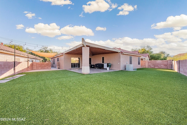 rear view of house featuring a yard, cooling unit, and a patio area