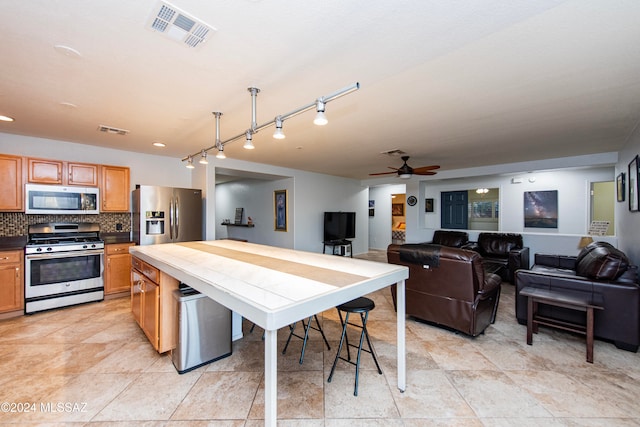 kitchen with decorative backsplash, ceiling fan, light tile patterned flooring, and appliances with stainless steel finishes